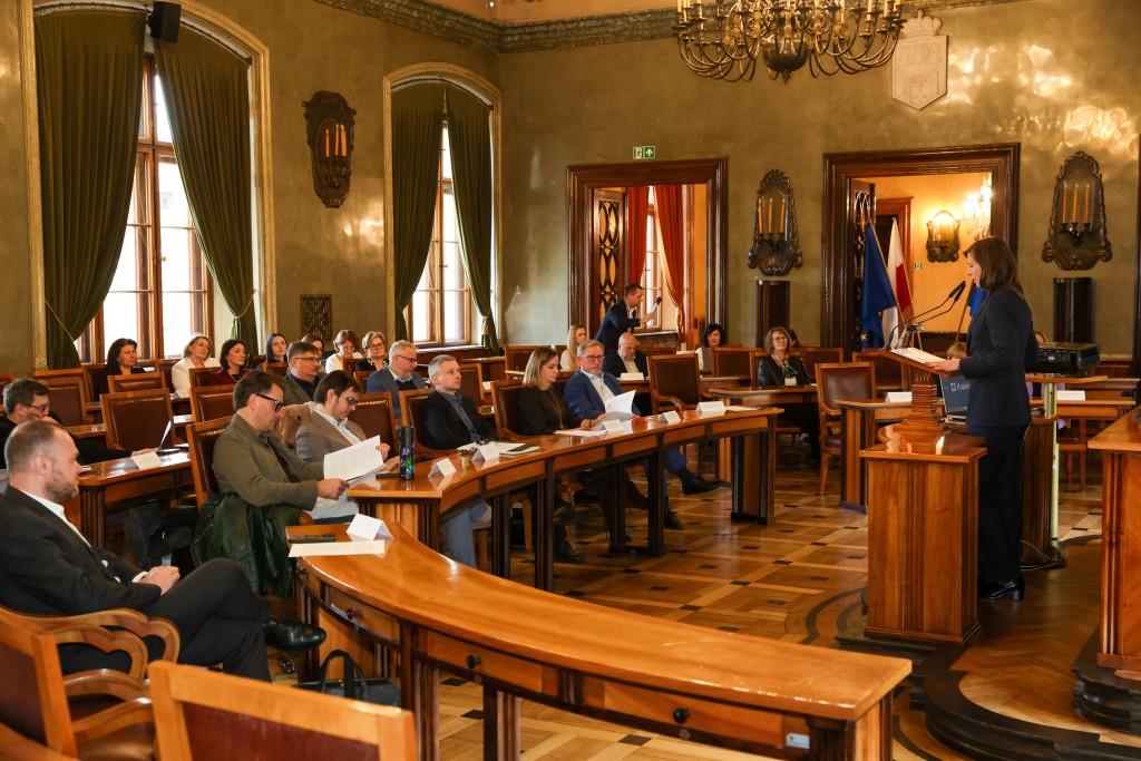 sala obrad, przy pulpicie osoba przemawiająca